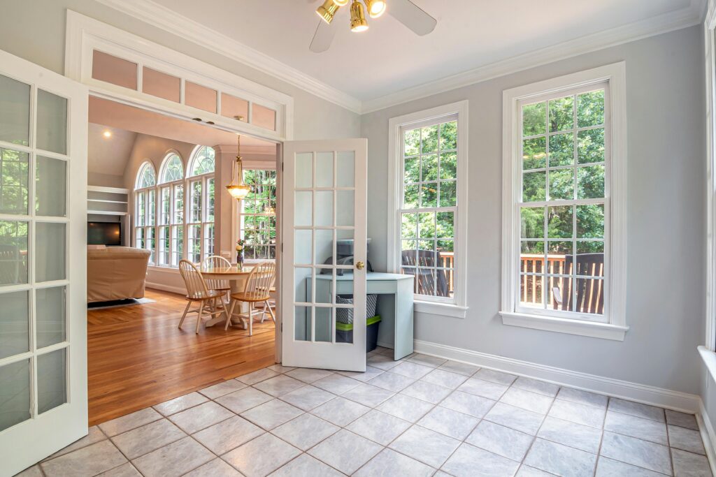 Bright living area showcasing elegant French doors, dining set, and lush outdoor view.